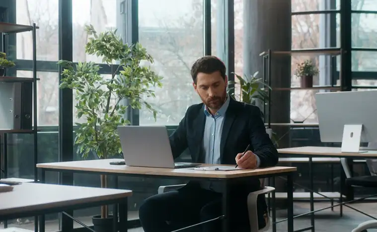 businessman typing laptop in office writing notes