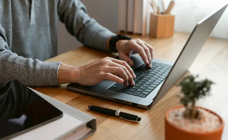 Close up of a business man typing on a laptop.