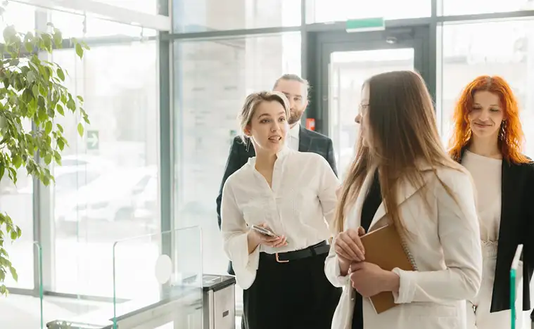 A group of business people walking through an office lobby.
