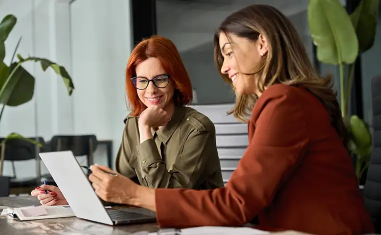 Two business women looking over a laptop.